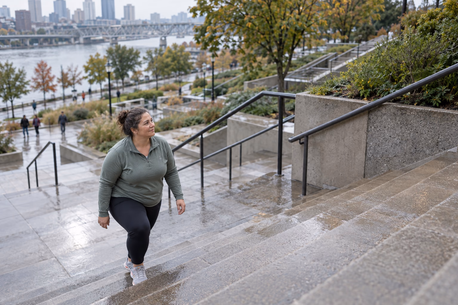 An adult climbs a rain-slicked public staircase in an urban waterfront park.